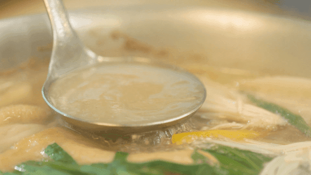 Vegetables and chicken broth in ladle