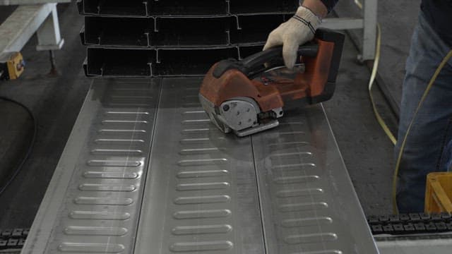 Worker using a tool on metal sheets