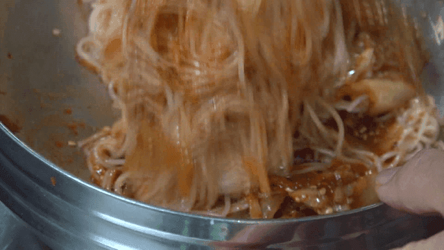In a metal bowl mixed kimchi bibim noodles
