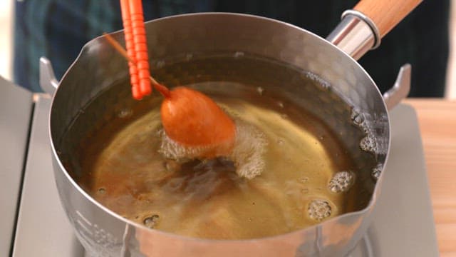 Cooking hot dog in hot oil in a saucepan