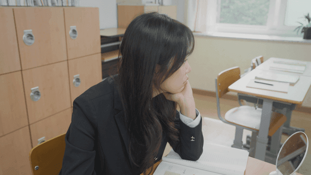 Student studying with his chin resting on his hand in the classroom