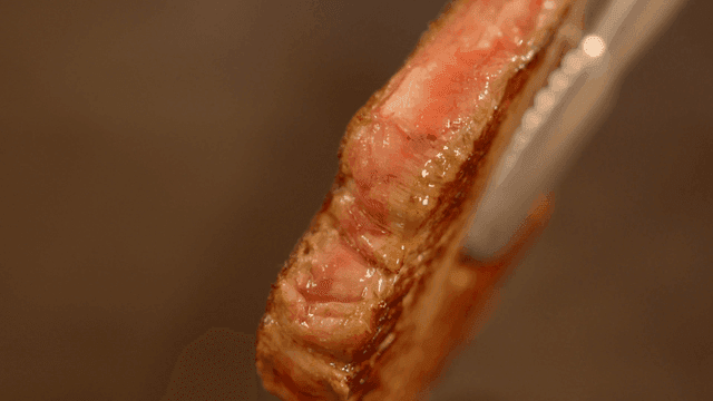 집게로 잡은 육즙이 많은 스테이크