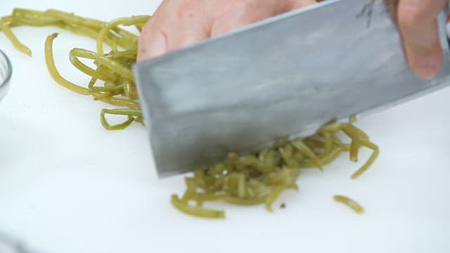 Chopping the boiled sweet potato stem on a cutting board with a large kitchen knife