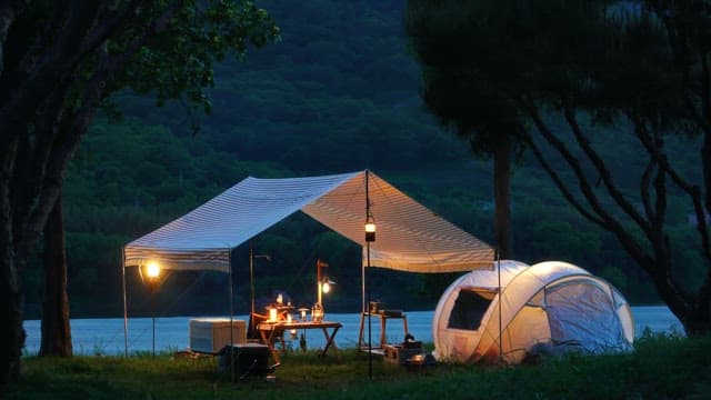 Camping equipments under tent canopy in a campsite beside a lake in the evening