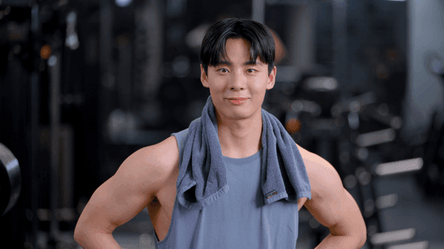 헬스장에서 수건을 목에 두르고 정면을 보는 젊은 남자