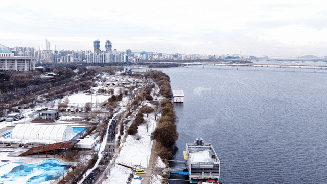 Snow-covered riverside park and city skyline