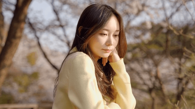 공원 난간에 기대어 생각에 잠긴 여성