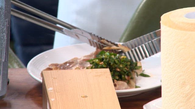 집게로 돼지고기에 시금치 무침을 싸는 모습