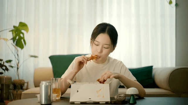 Happy woman eating seasoned chicken at home