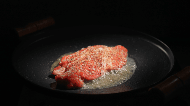 Steak sizzling in a hot pan
