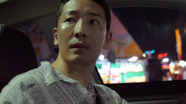 Man driving through a vibrant city at night