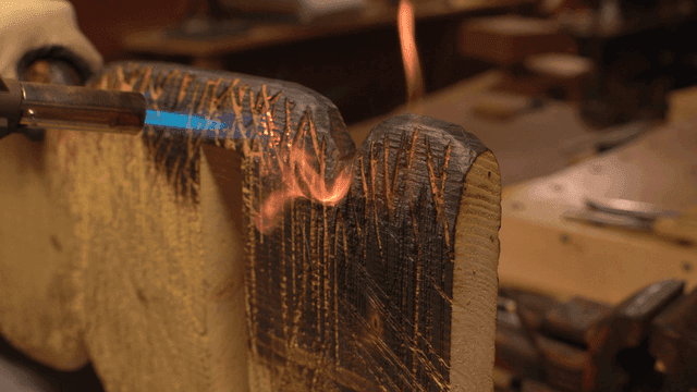 작업장에서 토치로 나무를 태우는 모습