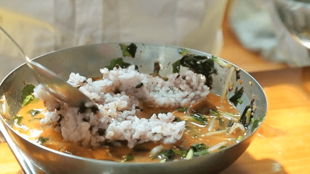 Mixing rice in a bowl of cold raw fish soup