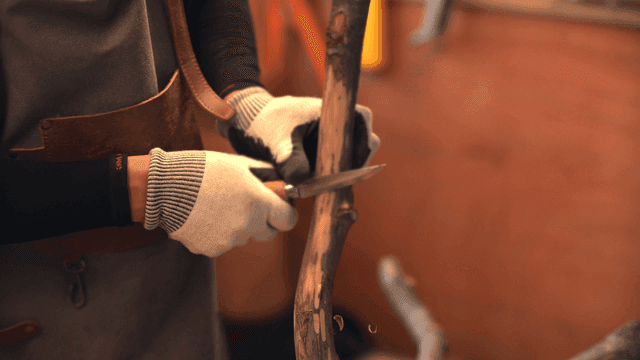 실내에서 나무 막대를 조각하는 사람