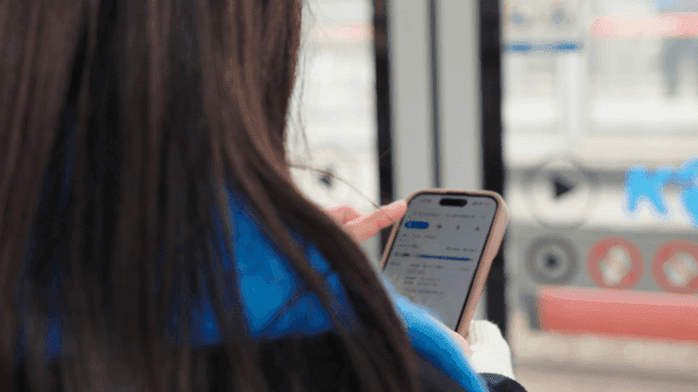 Woman's back view looking at a map on her smartphone on a subway platform