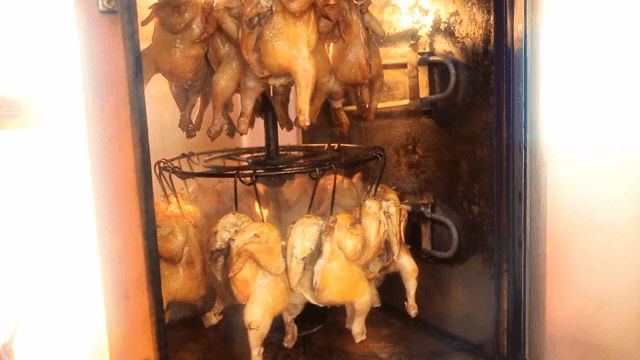 Rotisserie chickens roasting in an oven