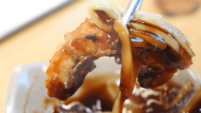 생강 간장 소스를 곁들인 장어구이를 집는 젓가락