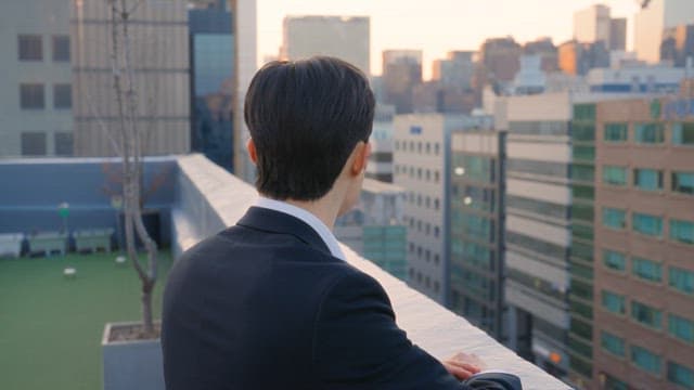 Man in a suit looking at buildings from a rooftop