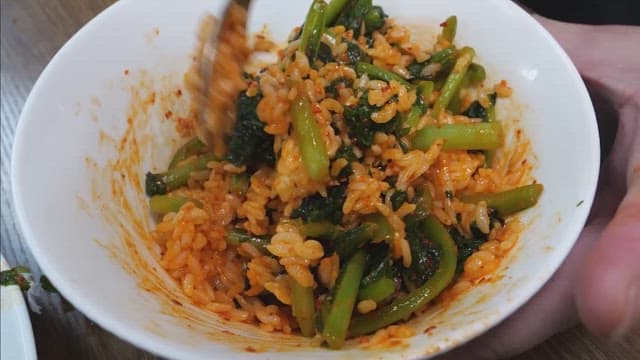 Mixing spicy young radish bibimbap in a bowl