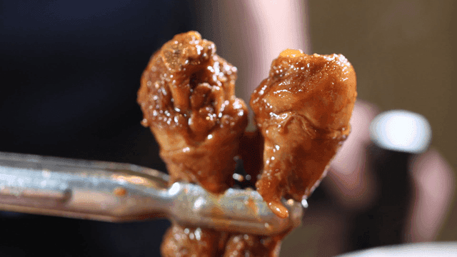 Jjimdak chicken leg lifted with tongs
