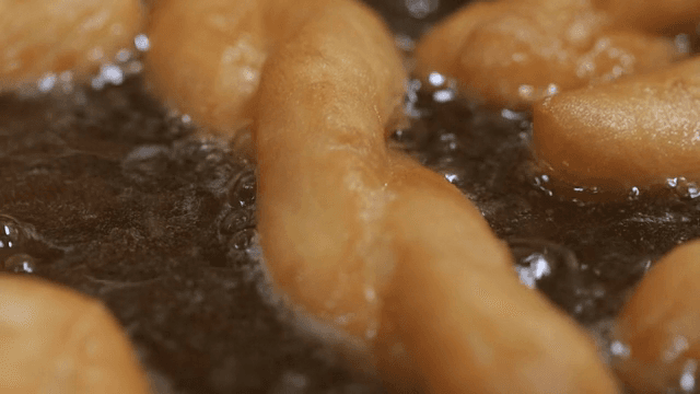 Twisted doughnuts frying in hot oil