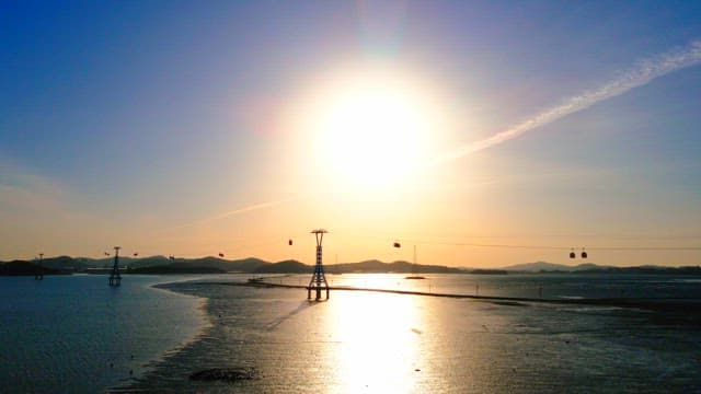 Scenic sunset over a calm sea with cable car towers