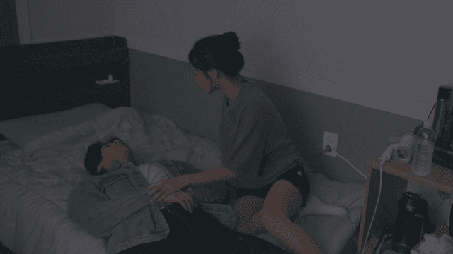 Woman putting a drunk man to bed