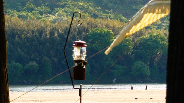 녹음이 우거진 강변에 걸려 있는 캠핑용 랜턴