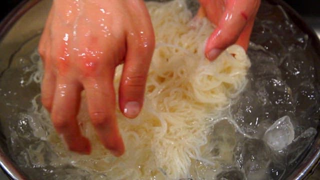 Hands washing noodles in icy water