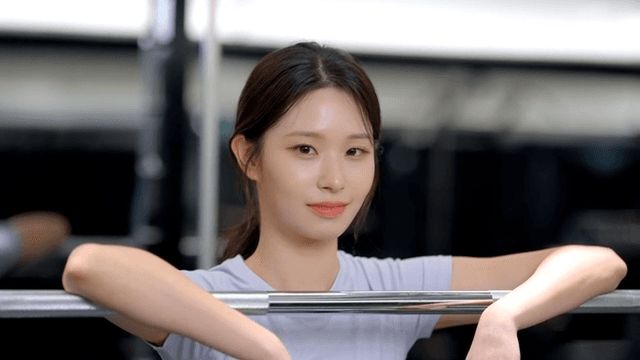 Young woman smiling while resting on a barbell at the gym