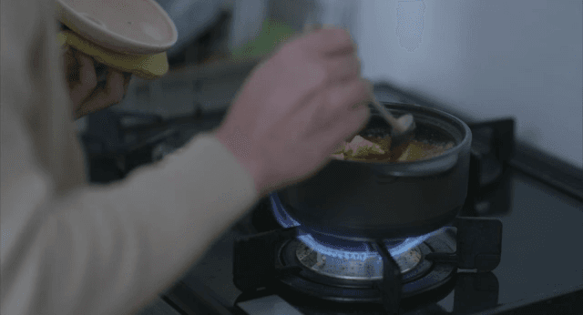 가스레인지에서 두부 된장찌개를 끓이는 손