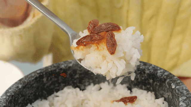 Spoon scooping out pot rice topped with dried goji berries