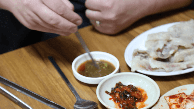 Person holding chopsticks to mix wasabi into soy sauce