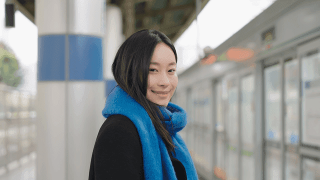 Woman smiling while looking straight ahead on a train station platform