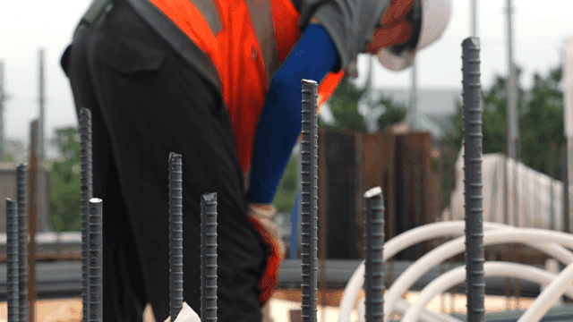 Construction worker bending over rebar
