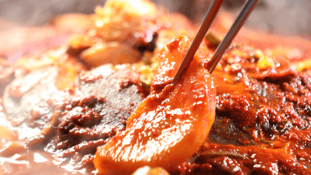 Chopsticks picking up radish from spicy braised duckfish