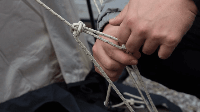 야외에서 로프에 매듭을 묶는 사람