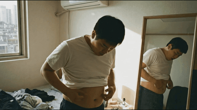 Man looking in mirror and checking his protruding belly