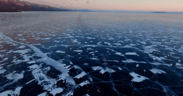 해질녘 얼어붙은 호수 위를 지나가는 차량