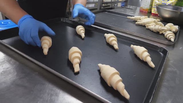 Placing croissant dough on a baking tray in an industrial kitchen