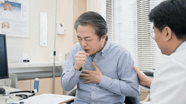 Elderly male patient coughing in doctor's office