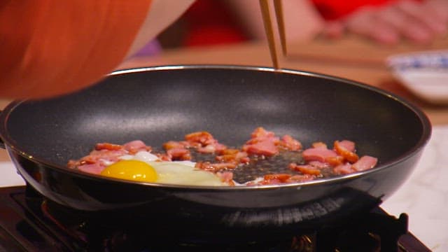 Fried eggs and smoked duck cooked in oil in a frying pan