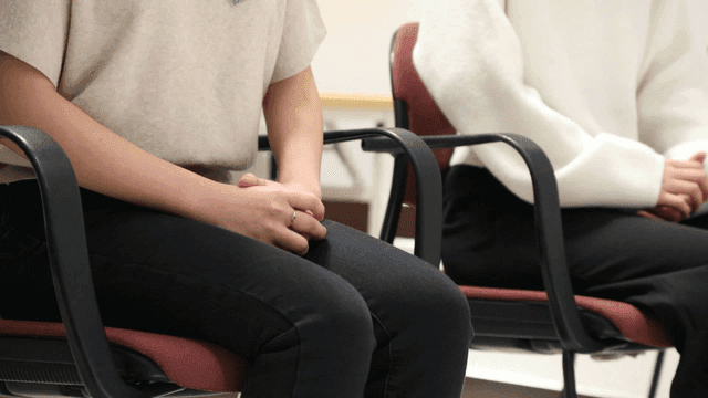 People speaking while sitting on chairs in interview room