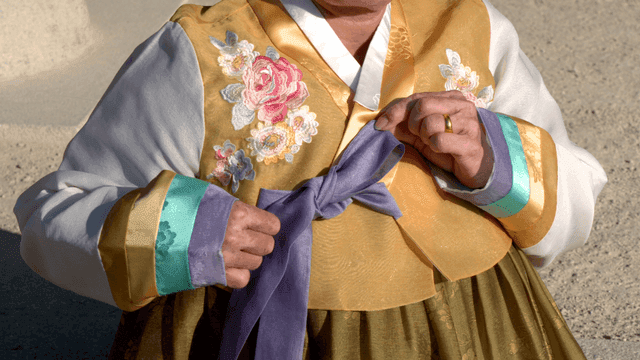 Elderly woman tying a hanbok ribbon
