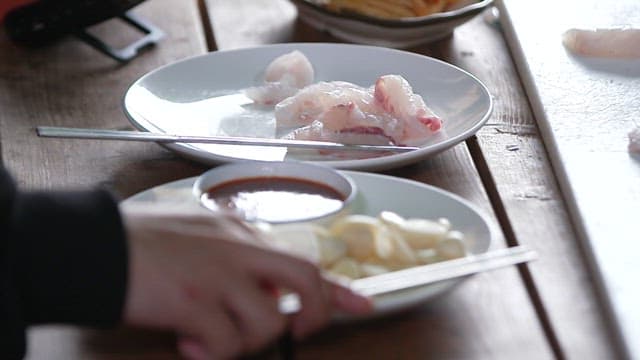Fresh raw fish being prepared for a meal on a rustic wooden table.