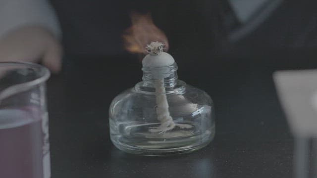 실험실에서 알코올램프로 실험을 하는 학생