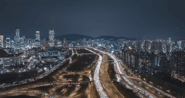 Bustling city night view and highway with cars speeding by