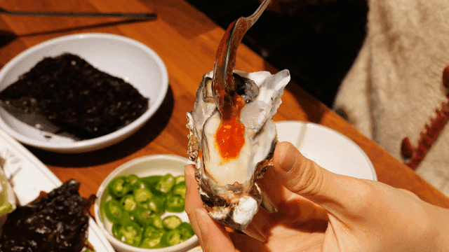 Raw oysters topped with spoon of chili sauce