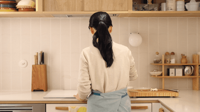 Back view of woman cooking food in kitchen