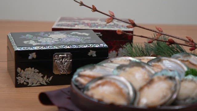 Abalones in traditional bowl on wooden table